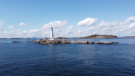 Boston Light located on Little Brewster Island in Boston, Massachusetts. The city skyline can be seen clearly in the background nearly 20miles away.