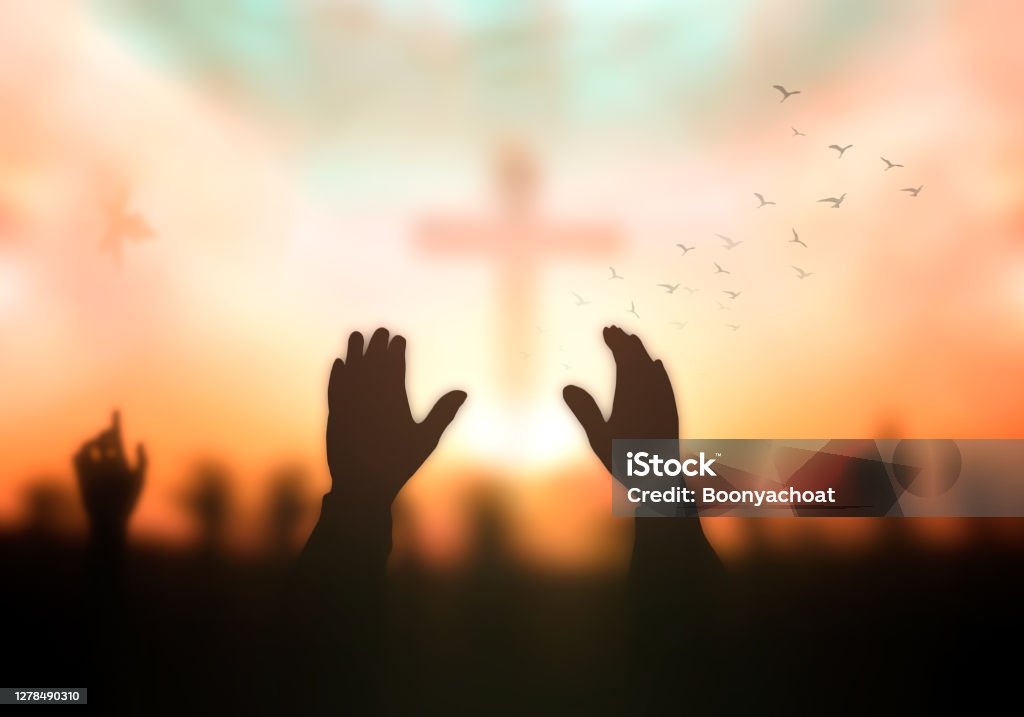 Worship God concept Silhouette christian hand rising over blurred cross on spiritual light background Praying Stock Photo