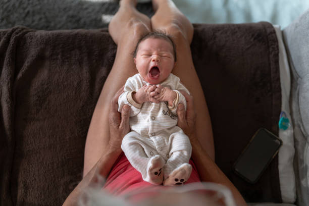 bébé nouveau-né bâillant tout en se trouvant sur les genoux de sa grand-mère - baby yawning asian ethnicity newborn photos et images de collection