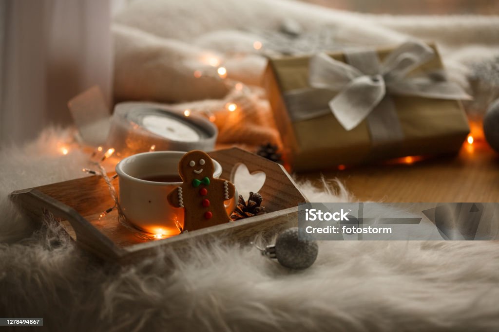 Warm tea and Gingerbread man cookie for a nicer Christmas day Copy space shot of a served cup of warm tea and a Gingerbread man cookie on a tray that is lying on a faux fur next to a Christmas gift. Abundance Stock Photo