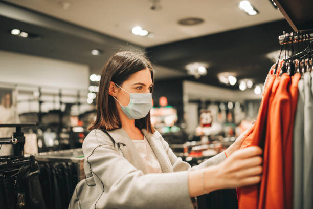 Happy woman with protective face mask at clothing store stock photo
