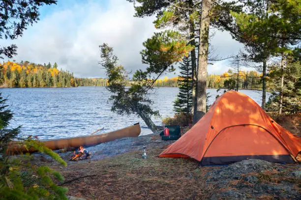 Campsite with orange tent on northern Minnesota lake at sunrise during autumn
