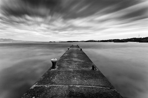 A concrete jetty or pier for fishing in Okinawa. A long exposure renders the water and clouds blurry.