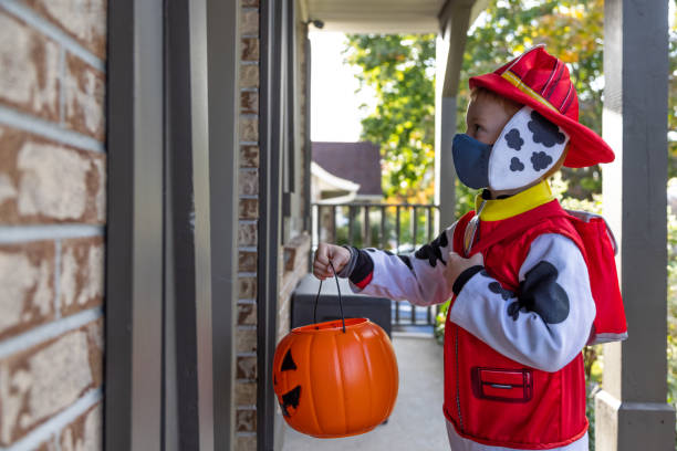 istock Young Boy wearing protective mask receiving candies on Halloween 1278500537