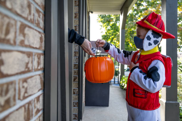 Young Boy wearing protective mask receiving candies on Halloween