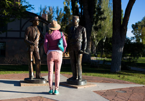 Los Alamos, NM: Tourist at Statues of Oppenheimer and Groves Los Alamos, NM: A tourist looking at bronze statues of J. Robert Oppenheimer and General Groves in downtown Los Alamos, where the atomic bomb was developed in the 1940s. los alamos new mexico stock pictures, royalty-free photos & images