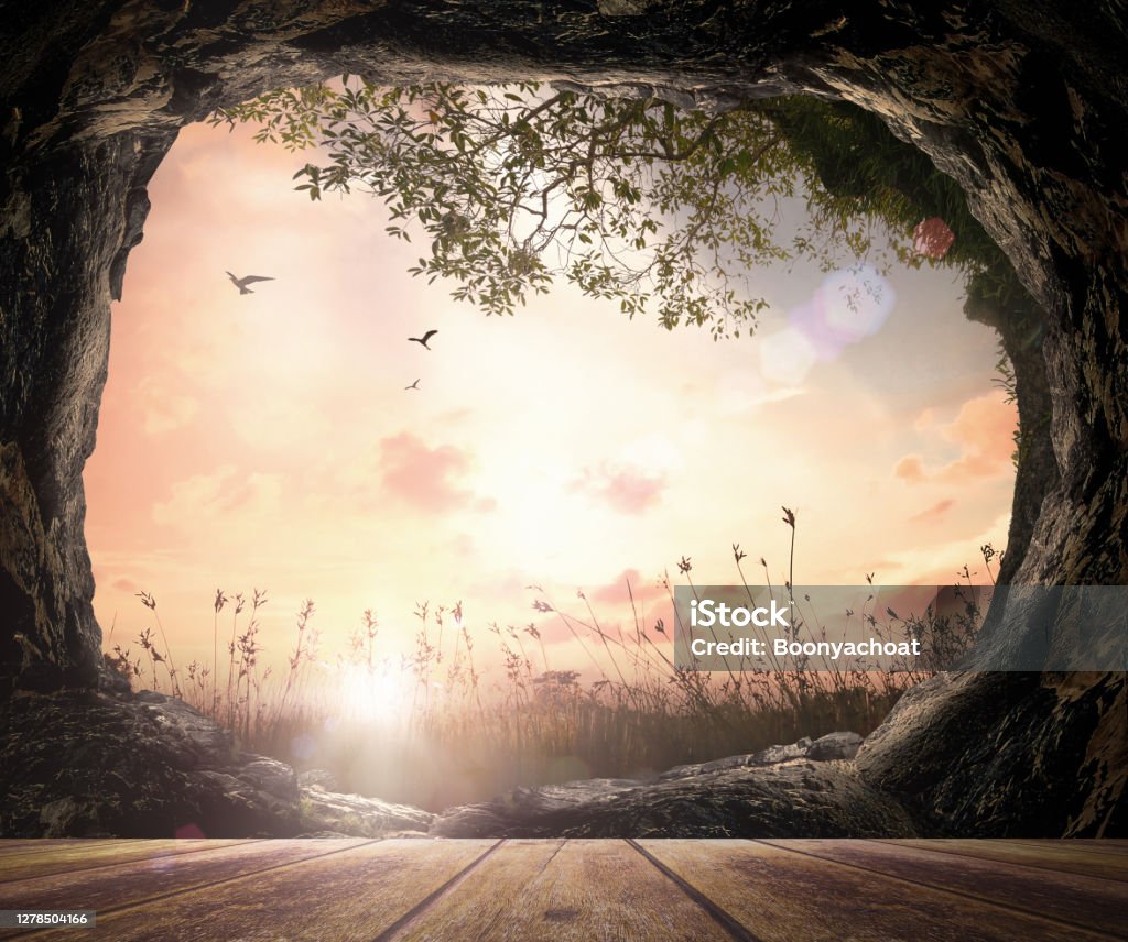 Easter Sunday concept Wooden table with open empty tomb stone on meadow autumn sunrise background Garden Stock Photo