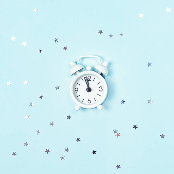 istock White vintage style alarm clock showing five minutes left until midnight over blue background. New Year advent. 1278517403