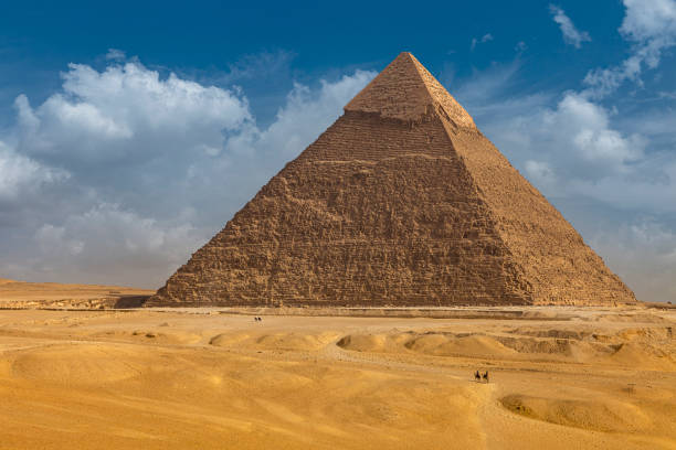 la carovana di cammelli si trova di fronte alle piramidi egiziane. - pyramid shape foto e immagini stock