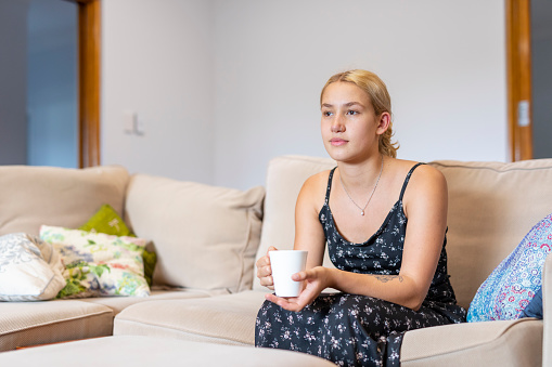 Young Maori Woman Sitting on the Sofa at Home With a Cup of Tea or Coffee