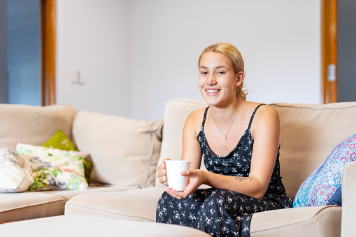 Young Maori Woman Sitting on the Sofa at Home With a Cup of Tea or Coffee
