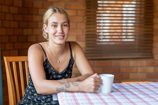 Young Maori Woman Sitting at the Dining Room Table With a Cup of Tea or Coffee