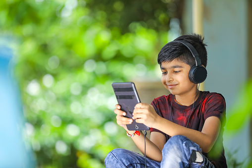 Indian / asian boy listening music or learning on mobile phone