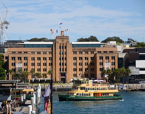 Sydney, Australia - February 9th, 2023: Sydney Harbor with Harbor Bridge, Sydney Ferries, and Cruise ship “Carnival Splendor” moored. Overcast weather.
