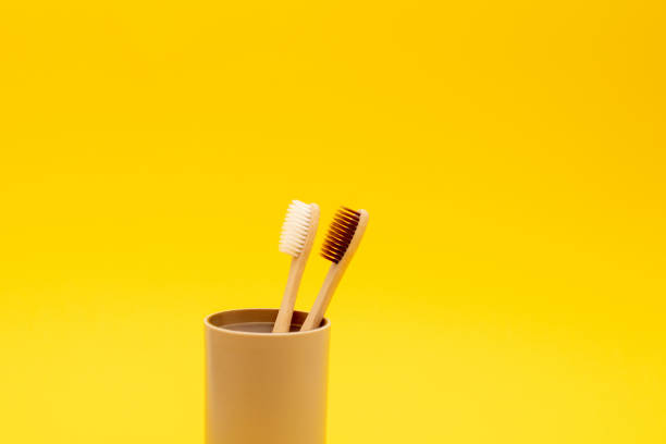 istock Eco friendly bamboo toothbrushes in glass on yellow background. Zero waste and Eco friendly 1278528218