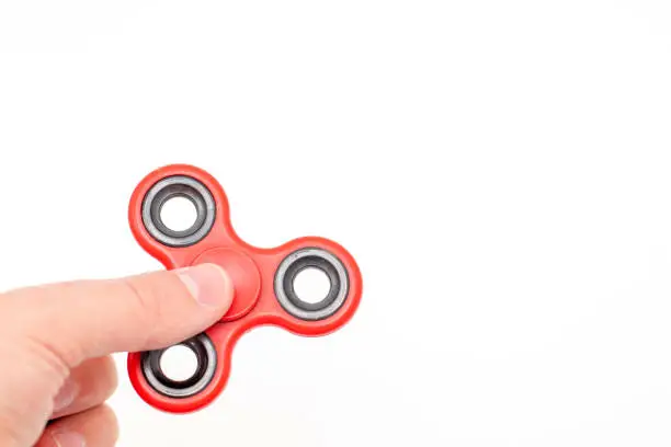Hand holding fidget spinner toy isolated on white background.