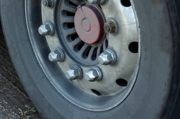 A close-up of a classic tractor wheel with chrome nuts. Dirty dusty truck wheel rim. Truck driver concept. Selective focus.