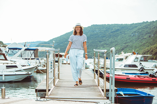 woman in white fashion luxury view walking by dock boats on background. summer time