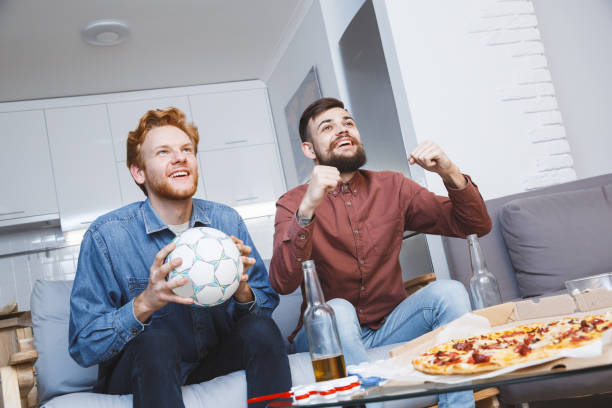 homens assistindo esporte na tv juntos em entretenimento doméstico - american football football food snack - fotografias e filmes do acervo