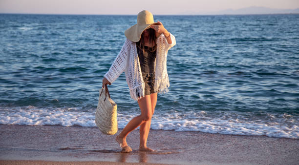 istock Beautiful boho model in a hat with a wicker bag on the beach 1278532756