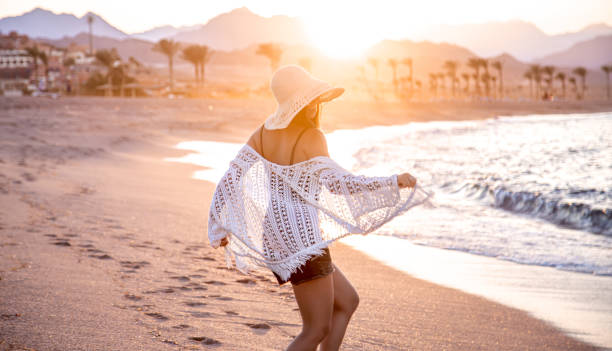 Woman at sunset on the beach in a hat.