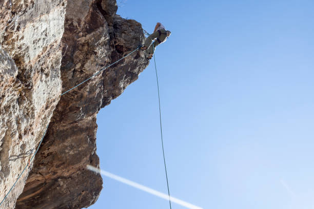 istock Young woman rappelling down from the cliff 1278533184