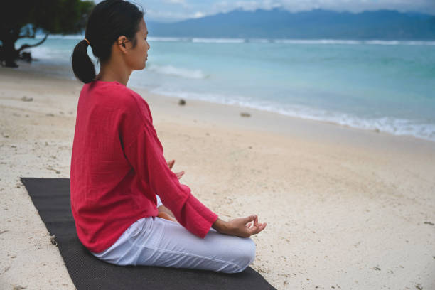 istock Woman meditates on beach 1278536805