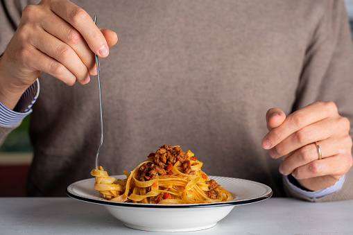 A man eating traditional italian pasta tagliatelle al ragù, also known as pasta bolognese. Life style photo.