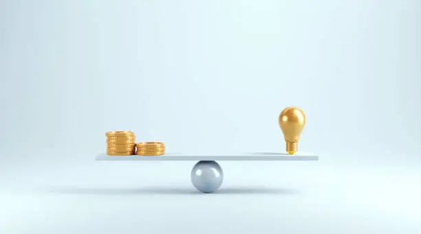 Photo of Idea vs coins on scales, Weights with light bulb and coins.