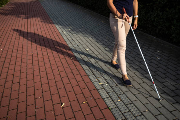 Blind woman walking on city streets, using her white cane