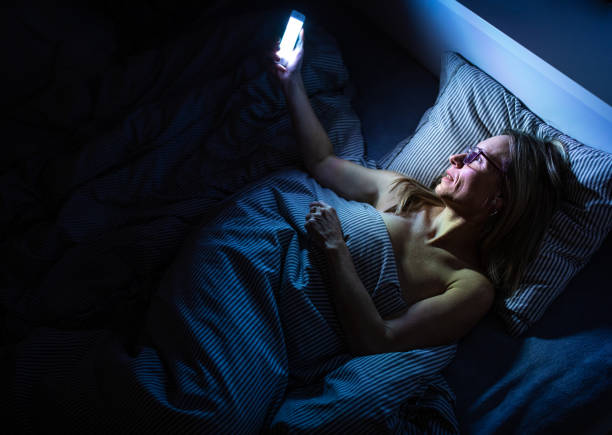 istock Pretty, middle-aged woman using her cell phone in bed at home 1278549434
