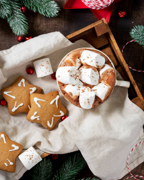 istock Hot cocoa or hot chocolate in a ceramic Cup on a wooden tray surrounded by gingerbread, Christmas tree branches and ornaments on a brown wooden table. Christmas Flatly 1278550190