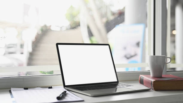 istock Mock up laptop with white screen on modern workspace with cup, book and document. 1278551265