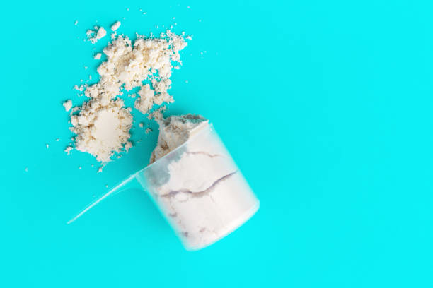 istock Scattered protein in scoop on blue background top view, copy space 1278551692