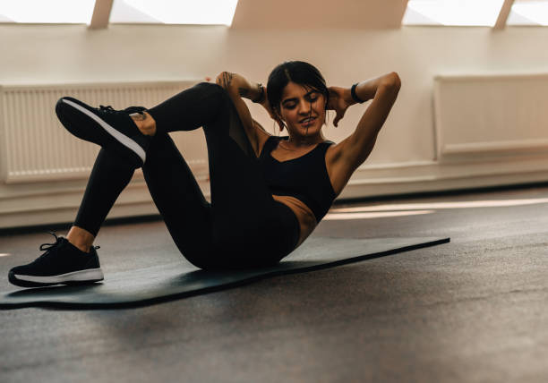 istock Female athlete with hands behind head doing abdominal exercise on mat in gym 1278552944
