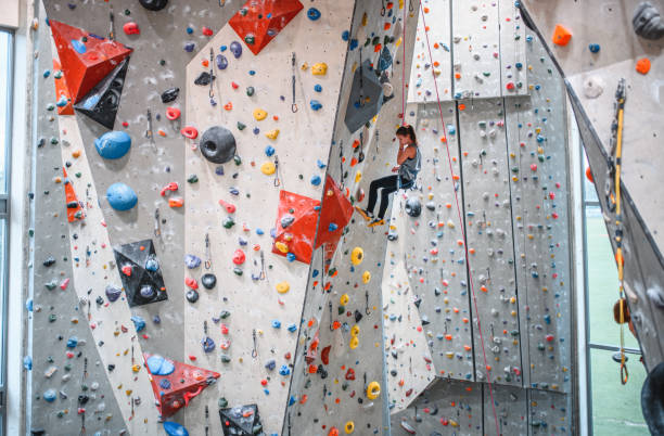 istock Child Climber Suspended by Rope While Scaling Wall in Gym 1278555635