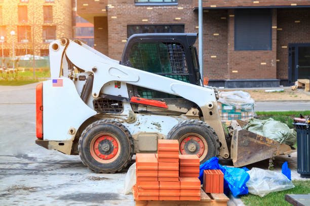 skid loader è nel cortile del nuovo edificio a più piani con sacchi della spazzatura in secchio - sbandare foto e immagini stock