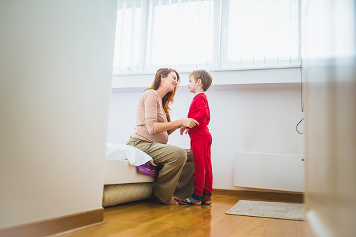 Pregnant woman helping son to get ready for sleeping