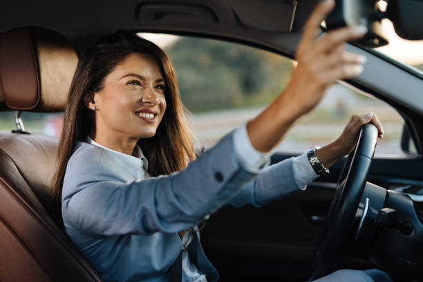 Beautiful female driver adjusting the rear mirror