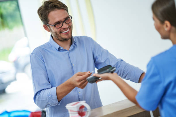 patient zahlt für zahnarztbesuch in klinik - healthcare and medicine receptionist paying credit card stock-fotos und bilder