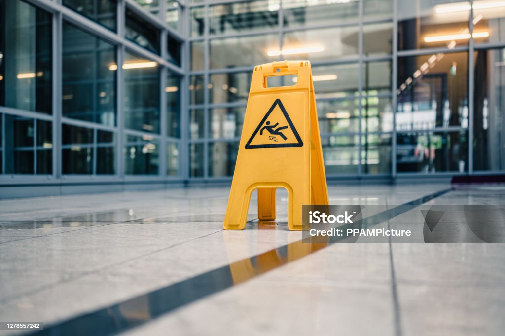 Warning sign slippery Yellow sign on floor that alerts for wet floor. Falling Stock Photo
