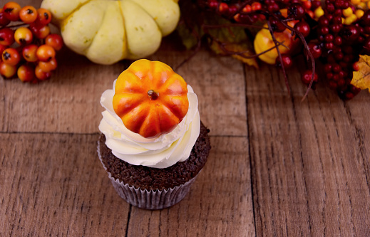 Pumpkin cupcake with vanilla cream stock images. Autumn still life with pumpkin cupcake. Sweet halloween decoration stock photo