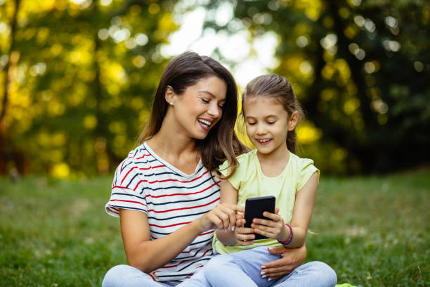 istock Mother and daughter using smart phone in the park 1278558121