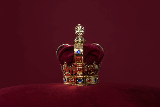 golden crown on a velvet cushion on a deep red background with copy space - red crowned imagens e fotografias de stock