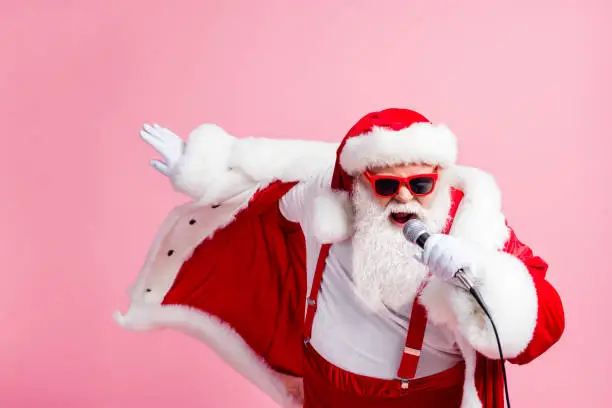 North-pole x-mas christmas celebrity grey beard santa claus sing microphone song, have newyear live concert wear headwear cap suspenders sunglass isolated over pastel color background
