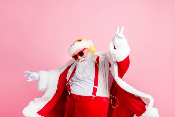 photo moderne funky santa claus écouter x-mas noël stéréo radio utiliser des écouteurs lever les mains mains porter le style élégant grand ventre costume pantalon couvre-chef isolé fond couleur pastel - santa claus audio photos et images de collection