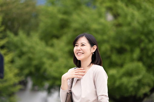 Asian businesswoman smiling and talking on street