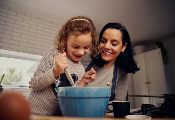 istock Happy mother and daughter preparing batter and dough while mixing with a whisk in kitchen - mother and daughter baking together 1278561586