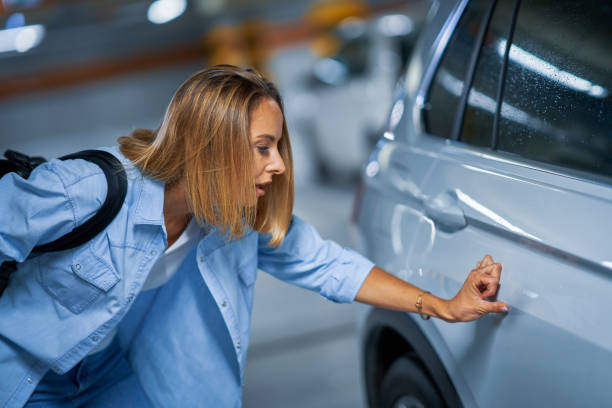 地下駐車場で傷ついた車を持つ若い女性の肖像画 - dented ストックフォトと画像