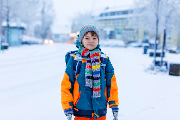 istock Happy kid boy having fun with snow on way to school 1278561931